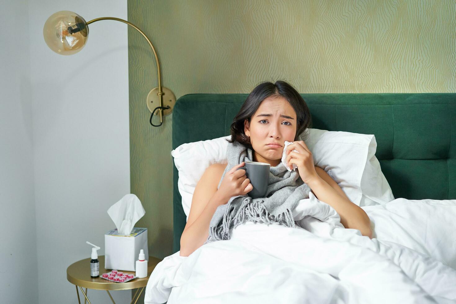 Gesundheit und Personen. asiatisch Mädchen Lügen im Bett, Gefühl krank, Niesen und Trinken heiß Tee, fangen kalt, bleiben beim Zuhause auf verlassen foto