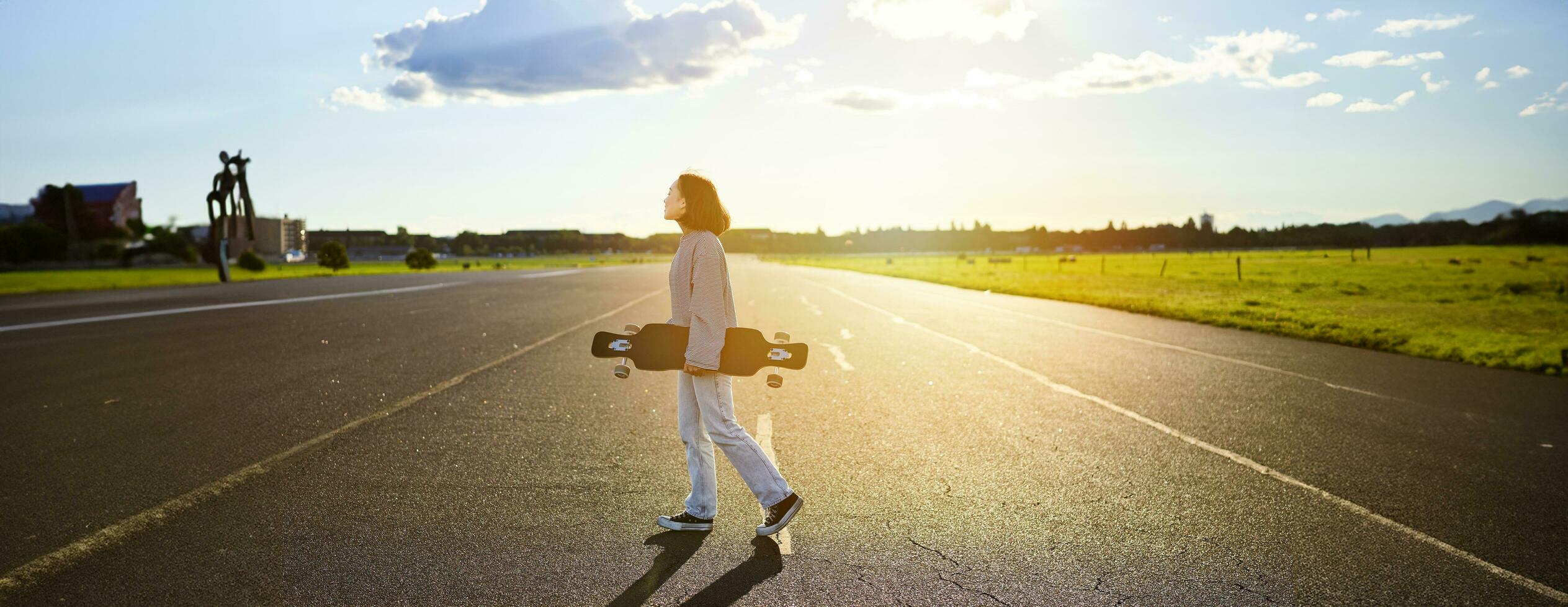 jung Skater Mädchen, Teenager Skaten auf Kreuzer, halten Longboard und Gehen auf Beton leeren Straße foto