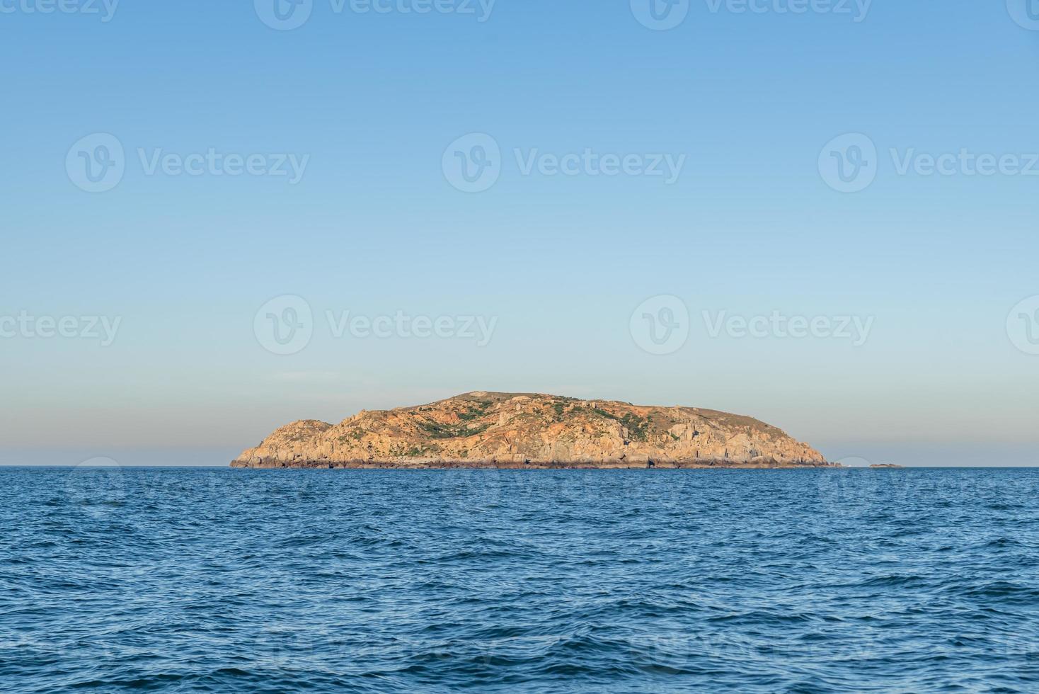 der Himmel ist klar und blau, die Insel mitten im Meer foto