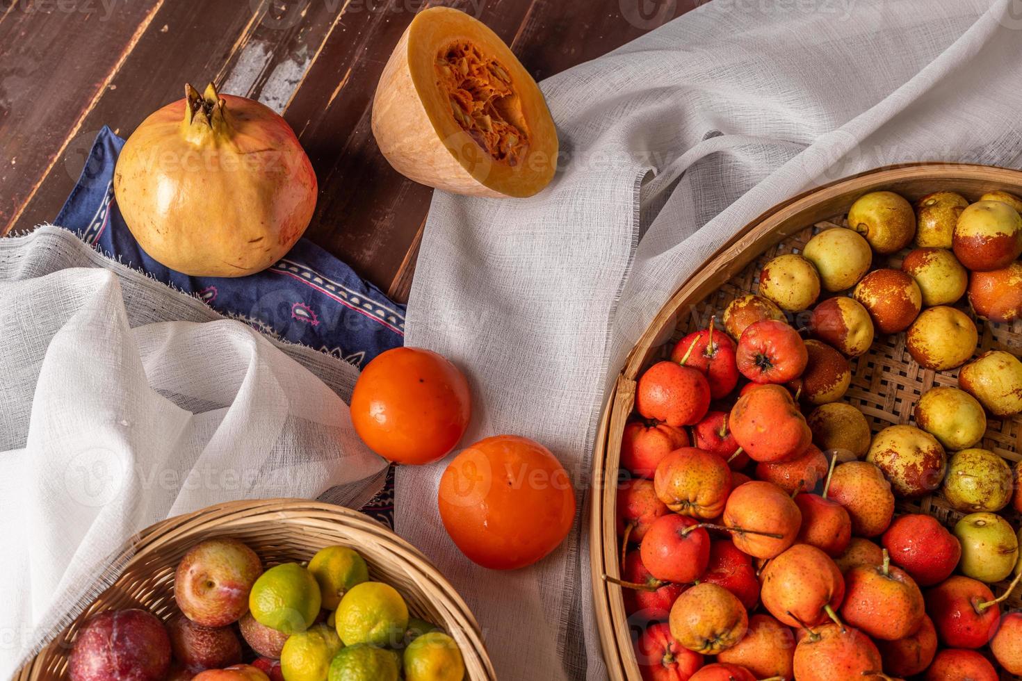 viele Farben und Obstsorten liegen entweder auf dem Teller oder verstreut auf dem Holztisch foto