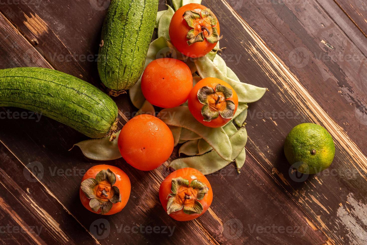 viele Farben und Obstsorten liegen entweder auf dem Teller oder verstreut auf dem Holztisch foto