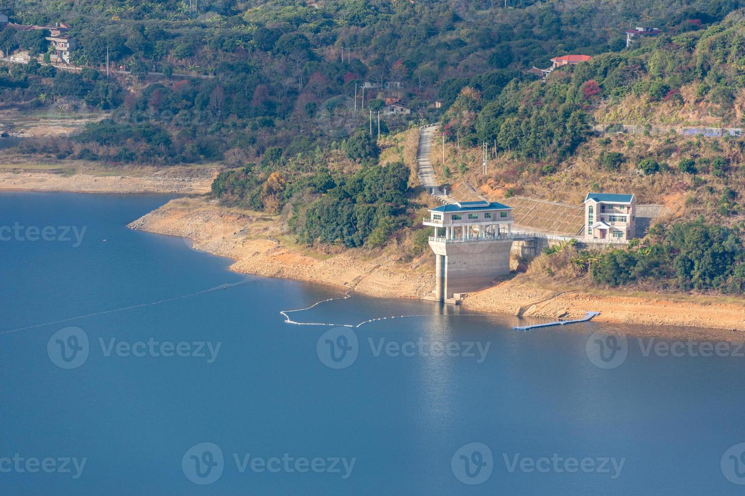 der Stausee unter blauem Himmel und weißen Wolken ist umgeben von Bergen und Wäldern foto