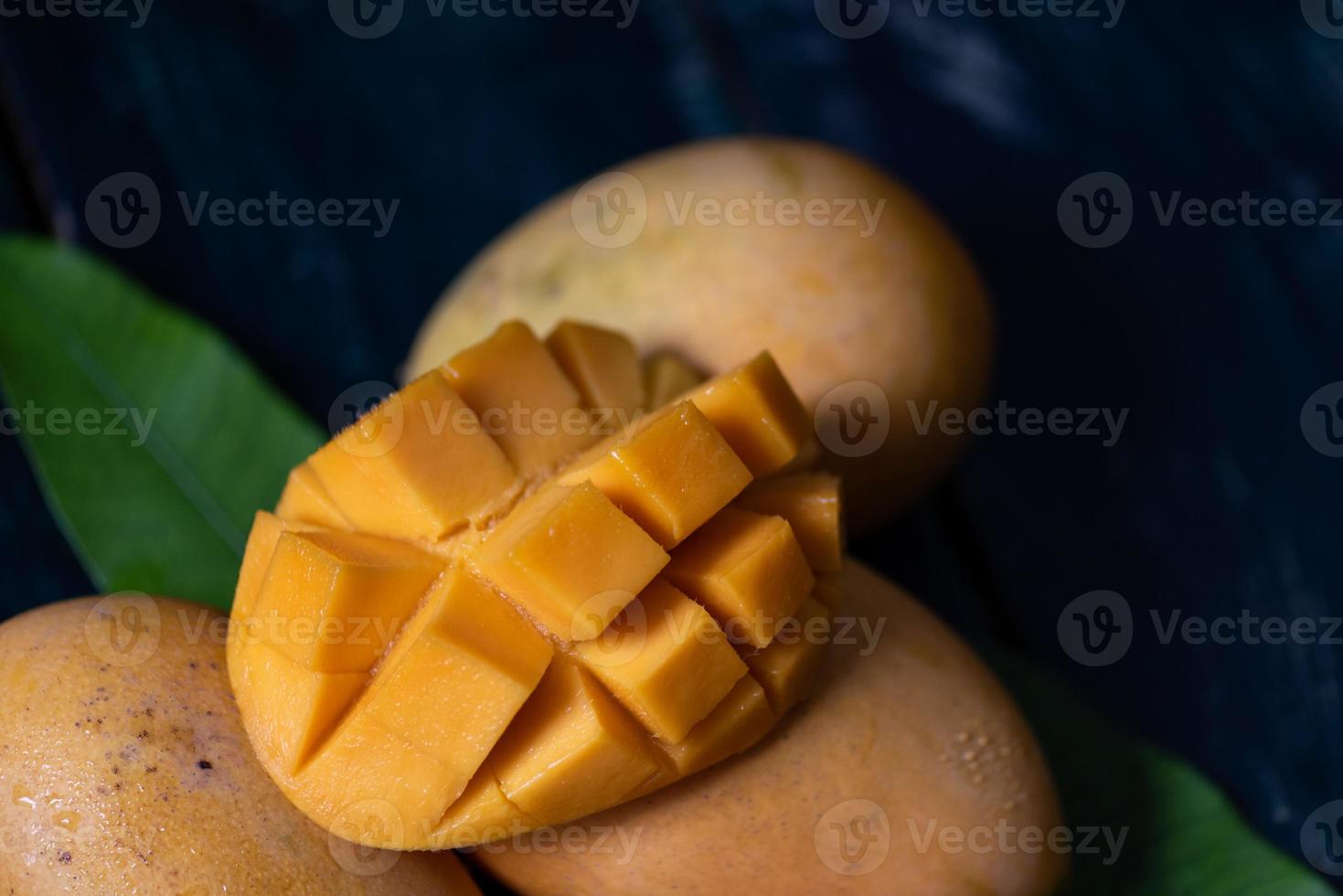 Schneiden und fertige Mangos auf einem Teller in einer dunklen Umgebung foto