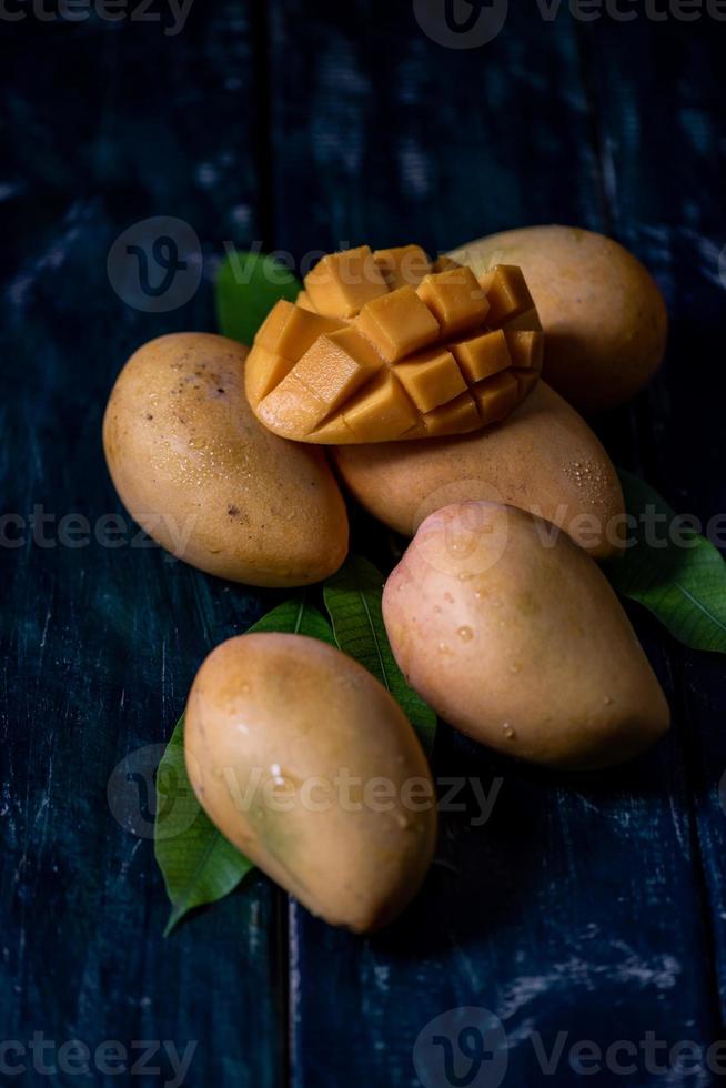 Schneiden und fertige Mangos auf einem Teller in einer dunklen Umgebung foto