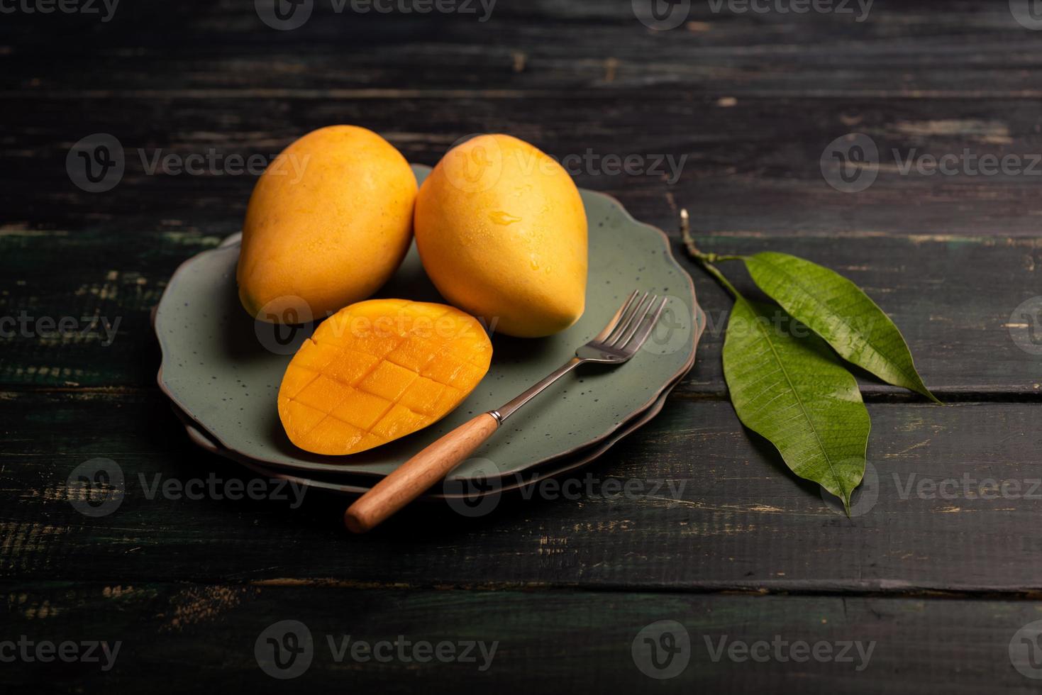 Schneiden und fertige Mangos auf einem Teller in einer dunklen Umgebung foto