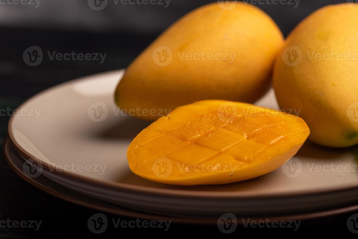 Schneiden und fertige Mangos auf einem Teller in einer dunklen Umgebung foto