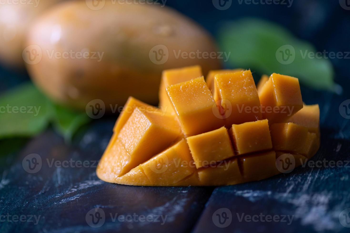 geschnittene und intakte Mangos im dunklen Hintergrund foto