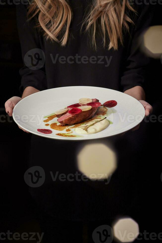 weiblich halten Teller mit gebacken Ente Brust mit Rote Beete, Daikon und Bechamel foto