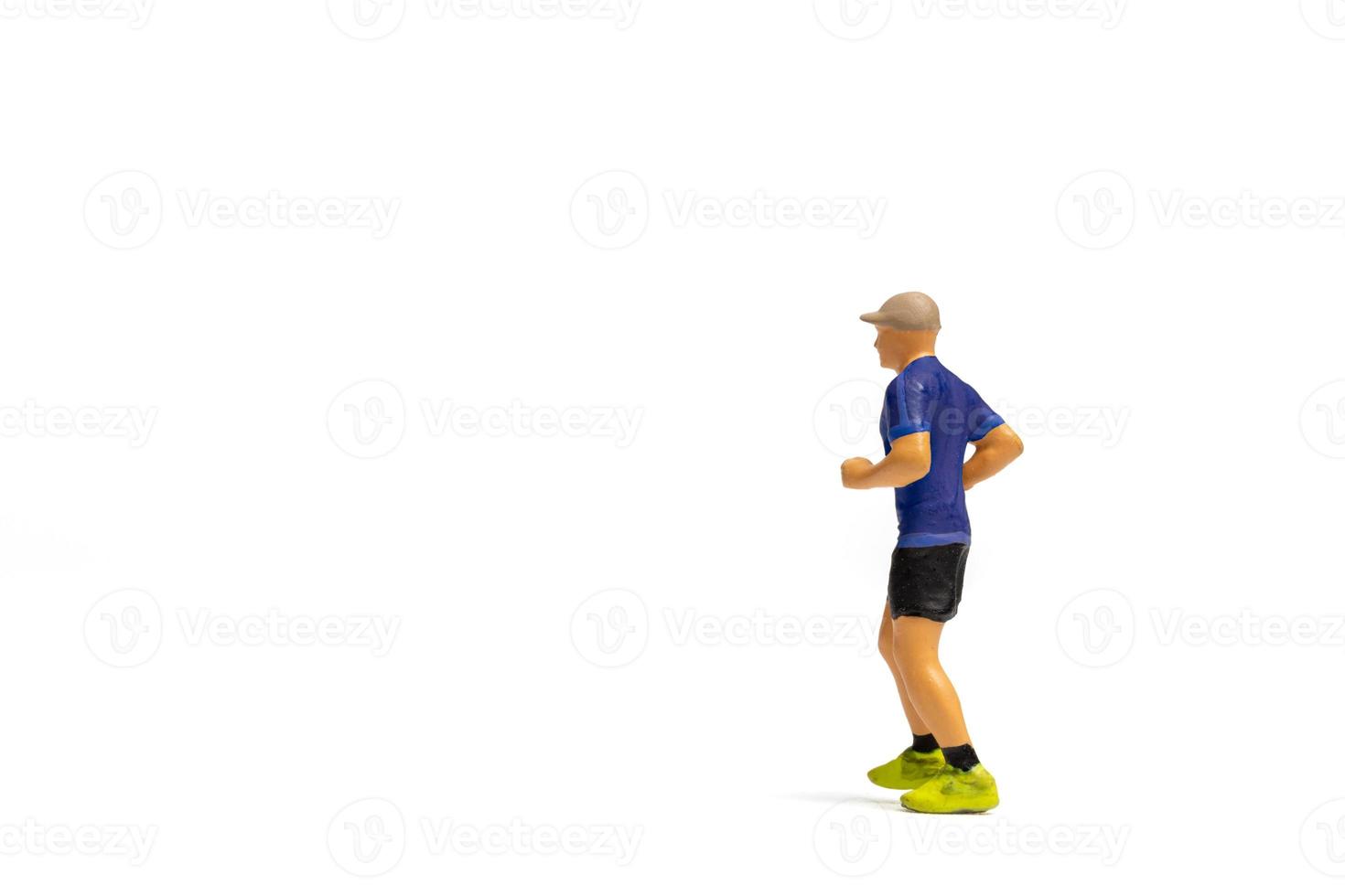 Miniaturmenschen, Mann in Fitnesskleidung, der auf weißem Hintergrund läuft foto