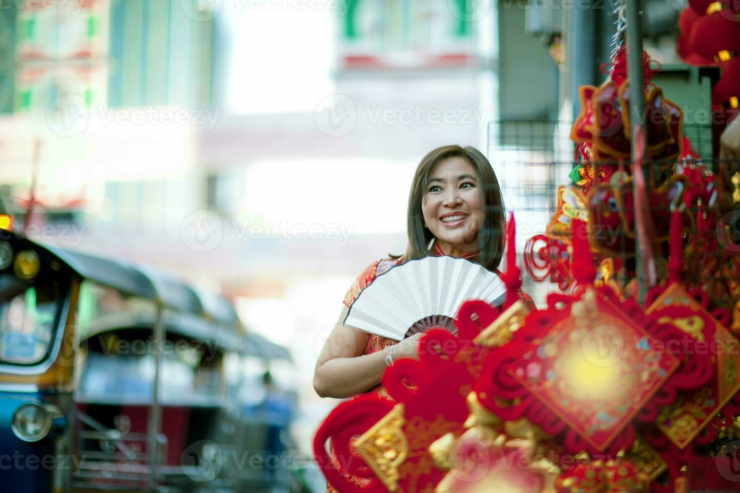 asiatische frau, die chinesische tradition kleidung mit chinesischem bambusfan trägt, zahniges lächelndes gesicht in yaowarat straße china stadt von bangkok thailand foto