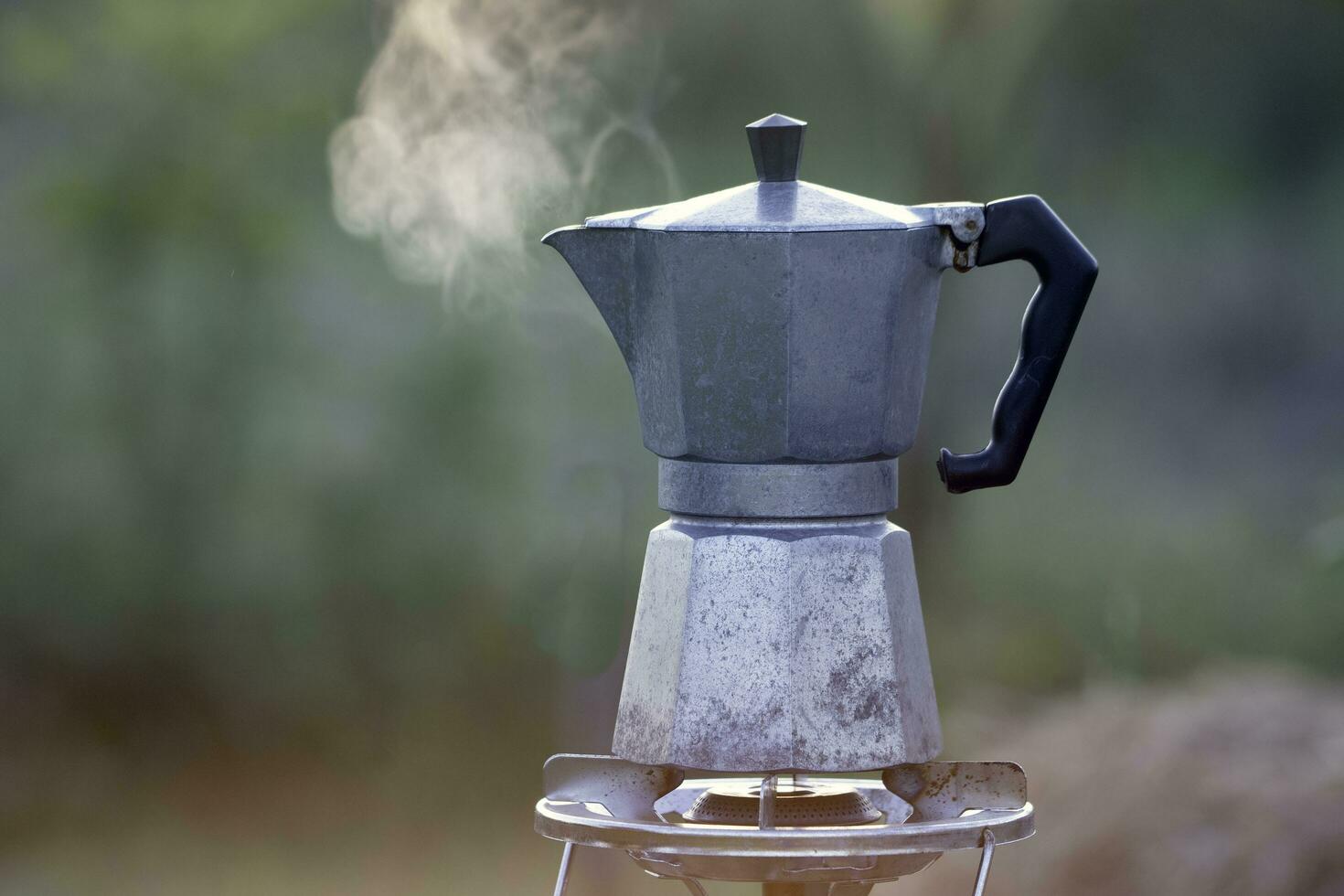 Moka Topf und Rauch, Kaffee sich aalen auf Feuer, im das Wald beim Sonnenaufgang im das Morgen. Sanft Fokus. flach Fokus Wirkung. foto