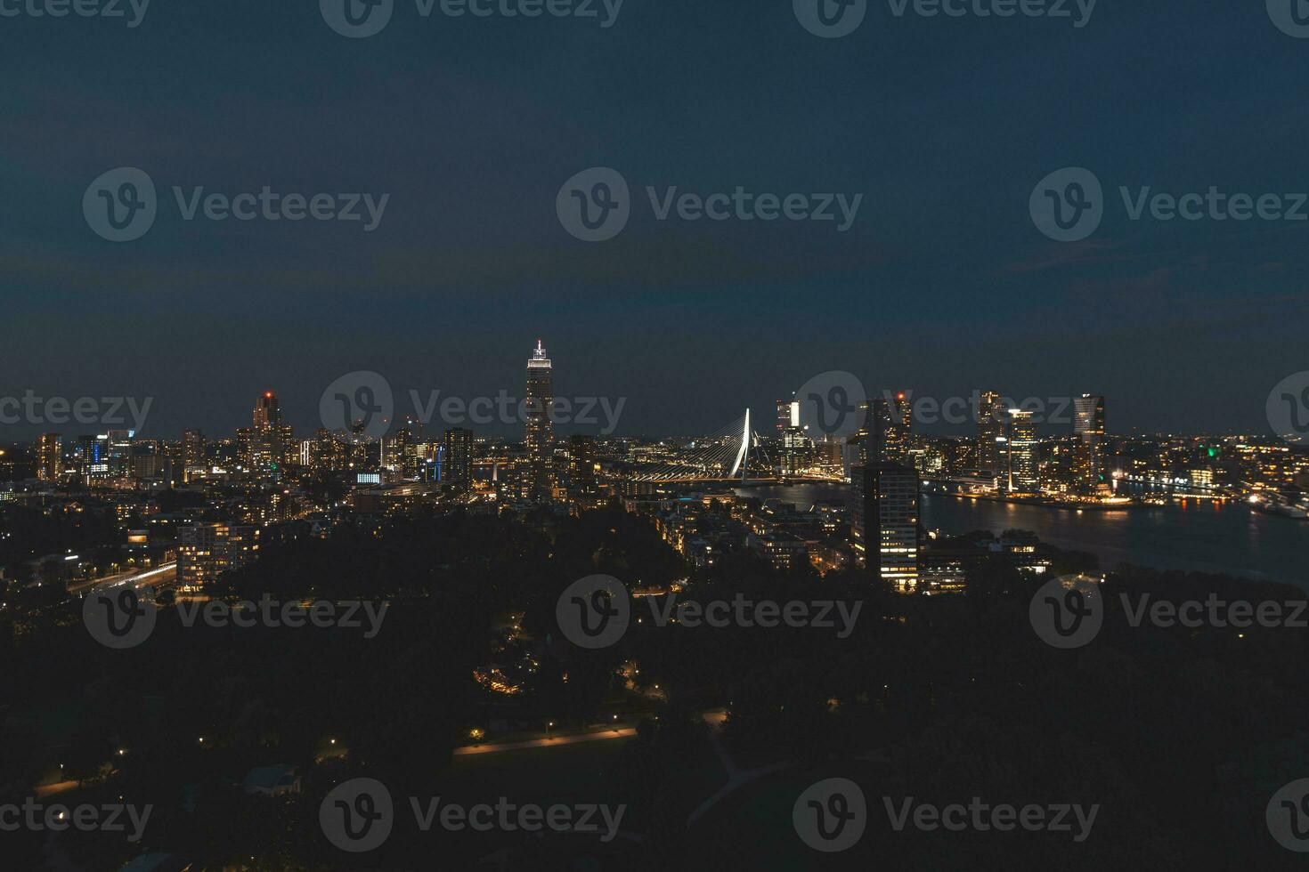 Nacht Antenne Aussicht von das schlaflos Stadt von Rotterdam und architektonisch Gebäude. glühend Wolkenkratzer und das berühmt Erasmusbrug Brücke. das modern Stadt von das Niederlande foto