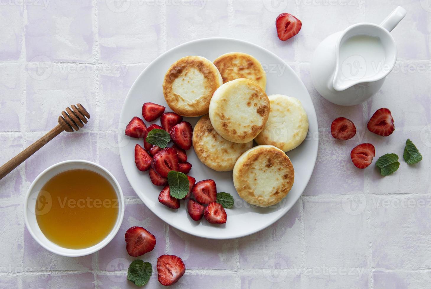 Quarkpfannkuchen, Ricotta-Krapfen auf Keramikplatte mit frischen Erdbeeren foto