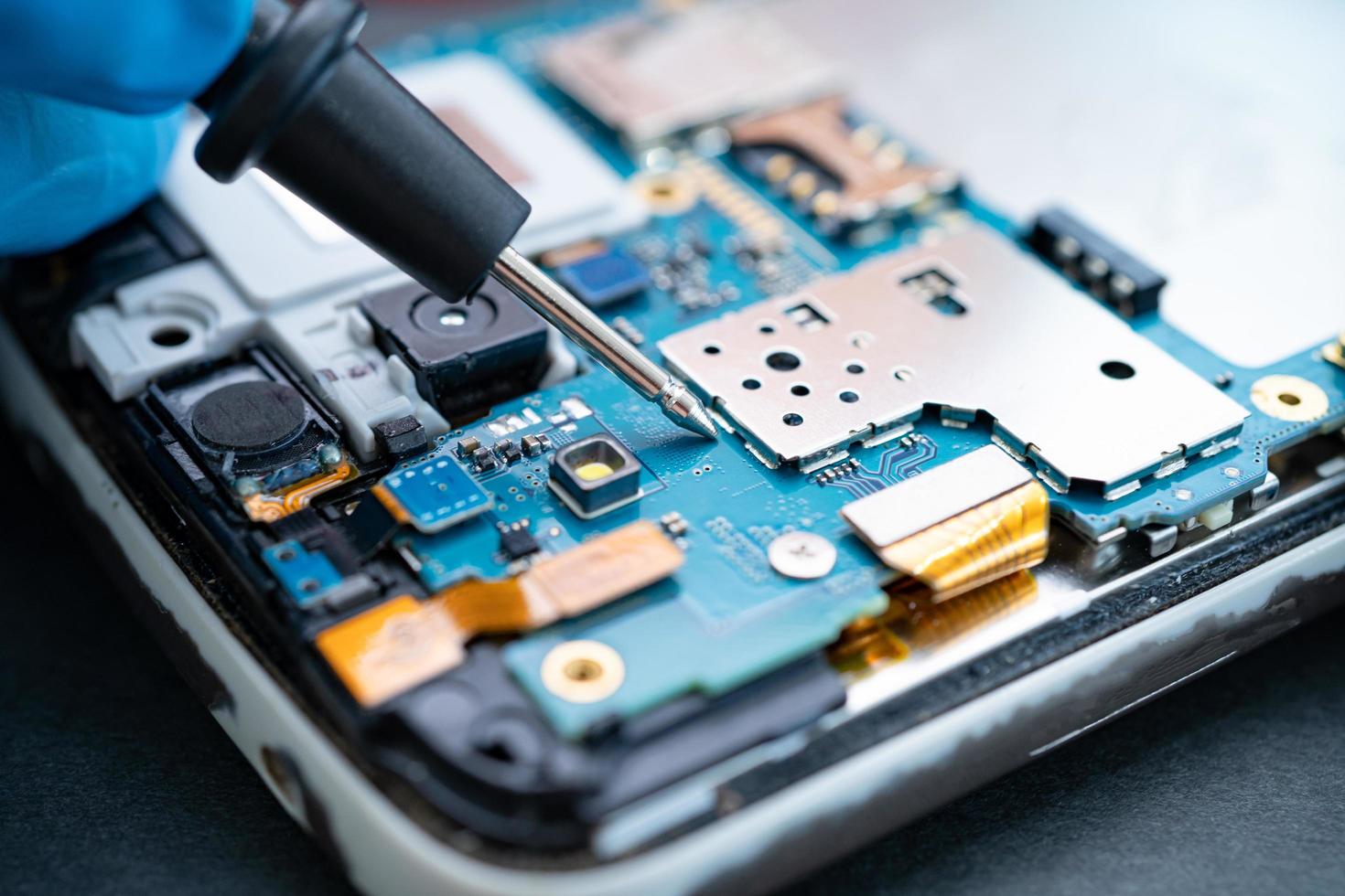 Techniker, der das Innere des Mobiltelefons durch Lötkolben repariert. Integrierter Schaltkreis. das Konzept von Daten, Hardware, Technologie foto
