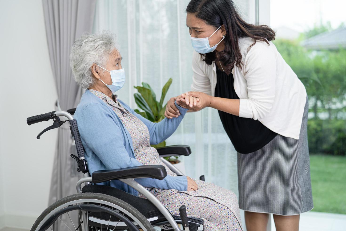 Helfen Sie asiatischen Senioren oder älteren alten Damen, die im Rollstuhl sitzen und eine Gesichtsmaske tragen, um die Sicherheitsinfektion des Covid-19-Coronavirus zu schützen foto