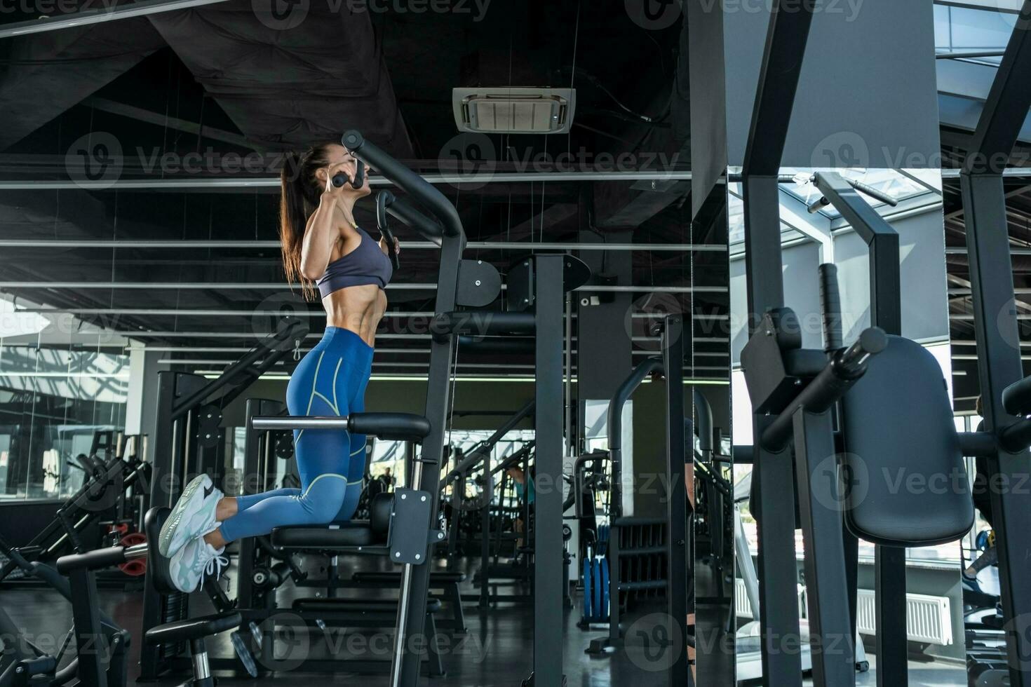 konzentriert sportlich Mädchen ziehen oben auf Maschine beim Fitnessstudio foto