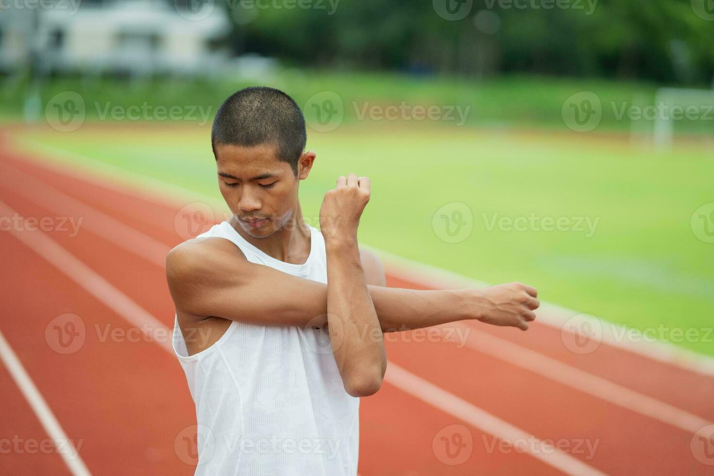 athleten sport mann läufer tragen weiße sportbekleidung zum dehnen und aufwärmen, bevor sie auf einer laufbahn in einem stadion üben. läufersportkonzept. foto