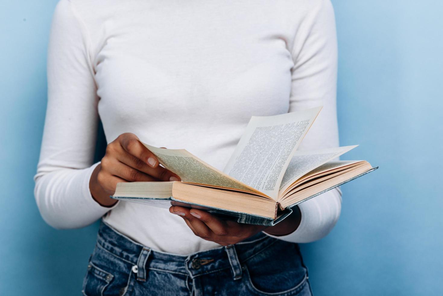 Nahaufnahme, Mädchen hält ein offenes Buch auf blauem Hintergrund foto