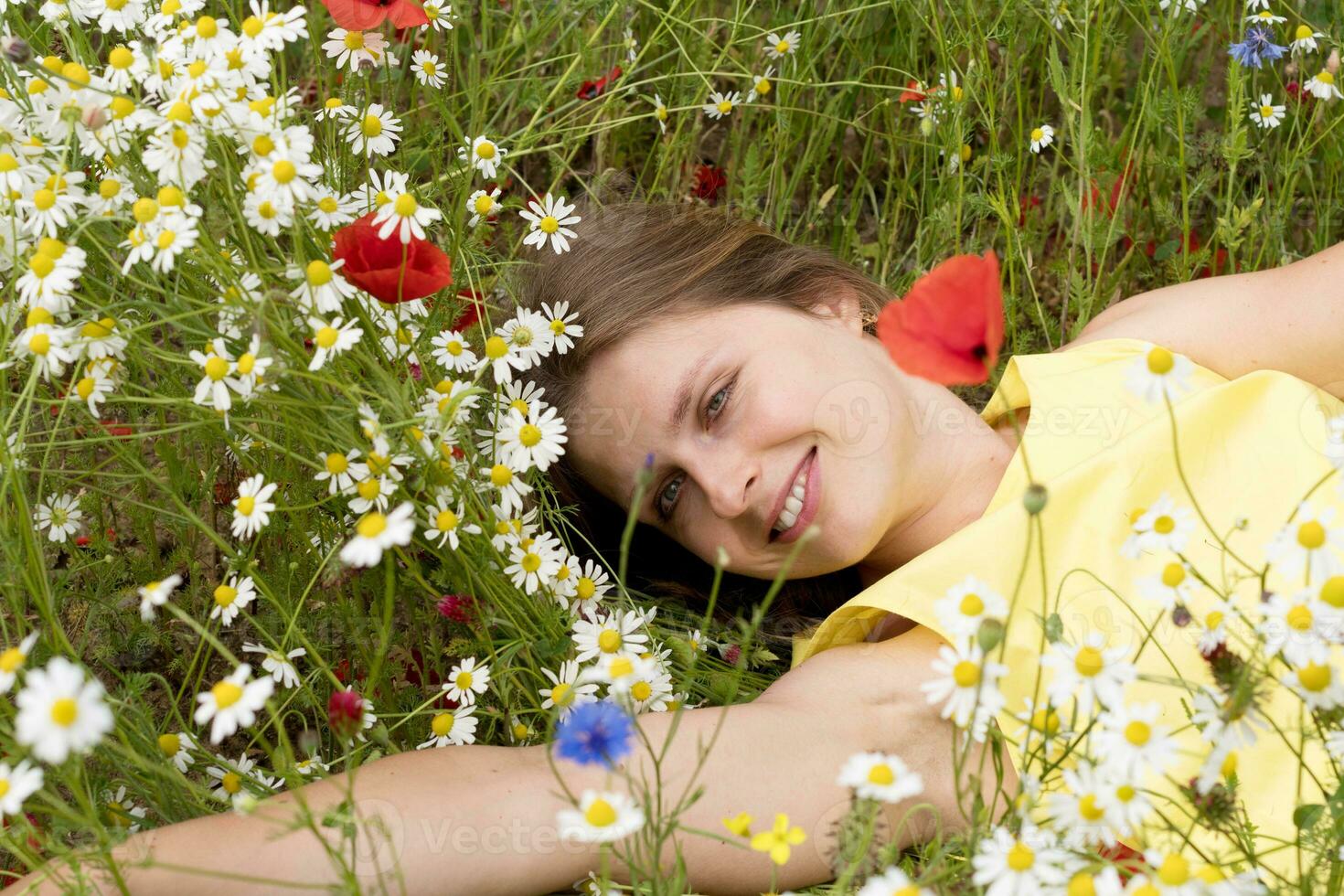 ein schön jung blond Frau im ein Gelb Kleid steht unter ein blühen Feld foto