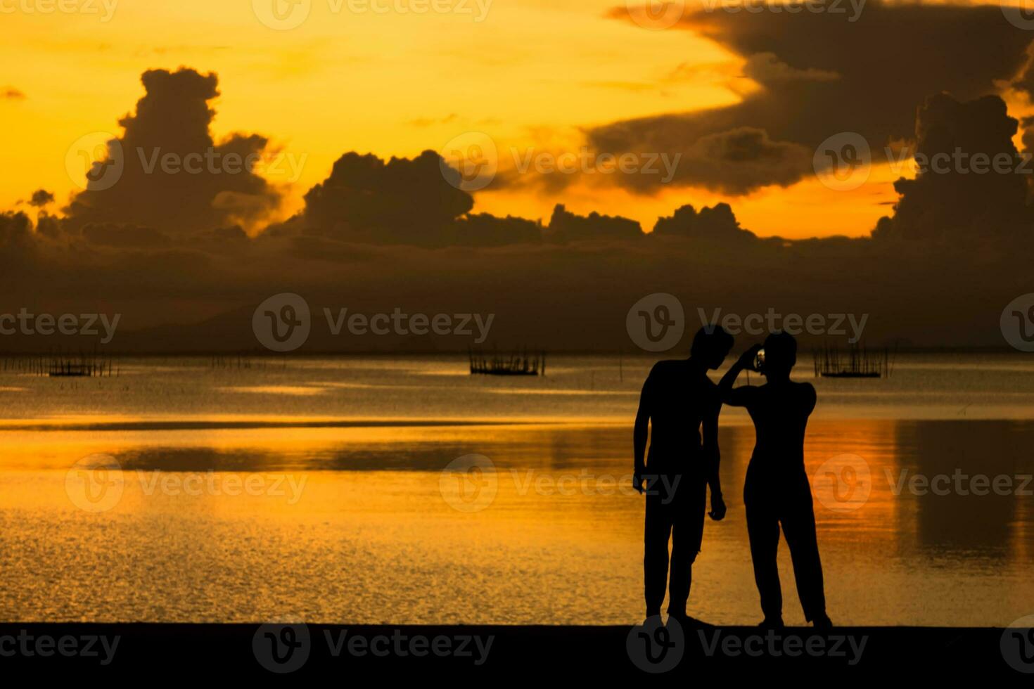 Silhouetten Menschen Schießen das Sonnenuntergang beim das See. foto