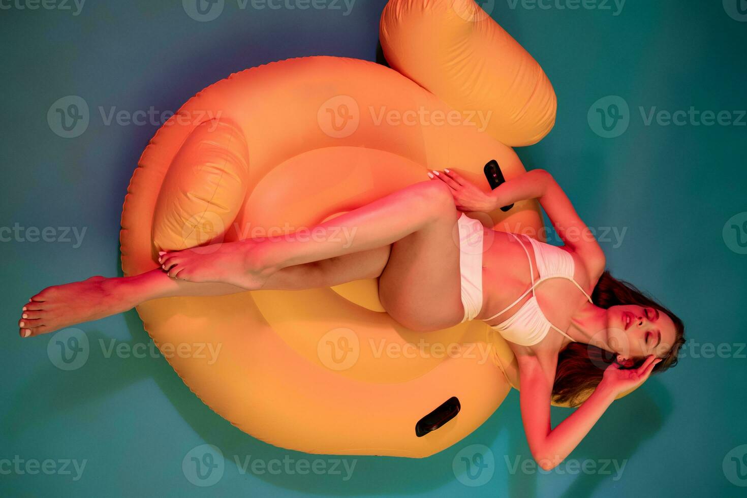 Mädchen im Badeanzug Lügen mit geschlossen Augen auf Gelb aufblasbar Schwimmbad schweben foto