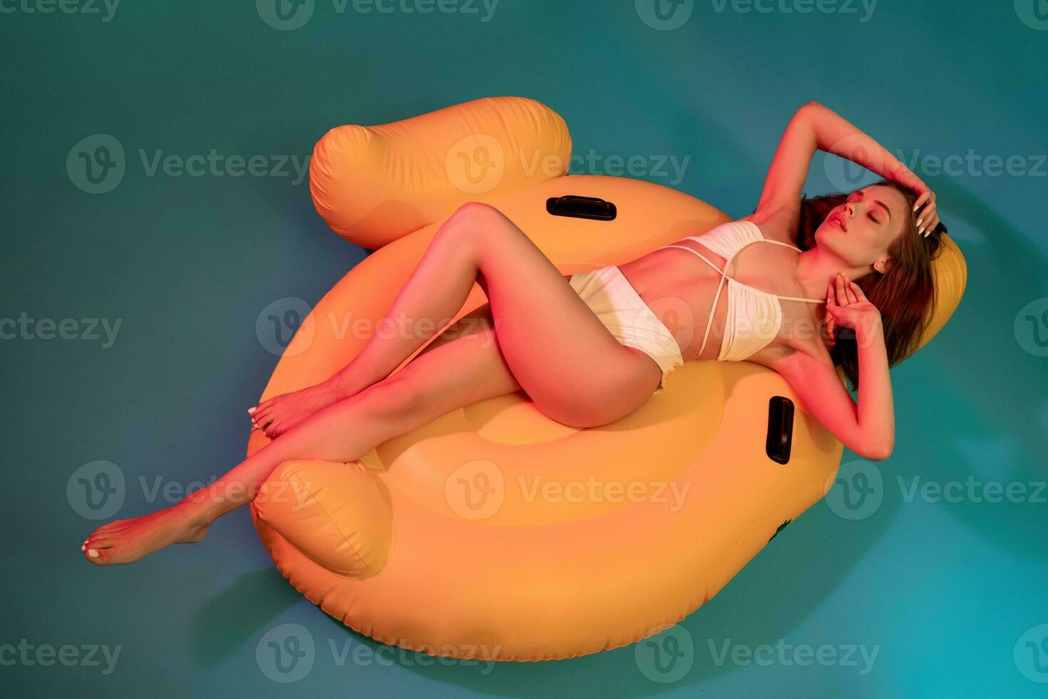 Frau im Badeanzug Lügen mit geschlossen Augen auf Gelb Luft Matratze foto