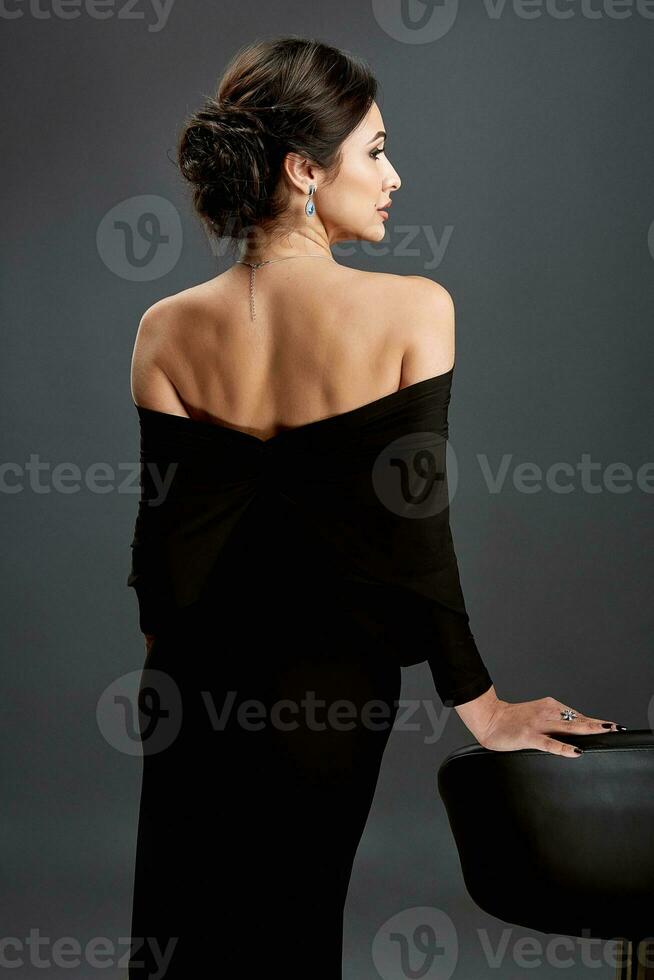 schön Frau Stehen im ein schwarz Kleid Über grau Hintergrund foto