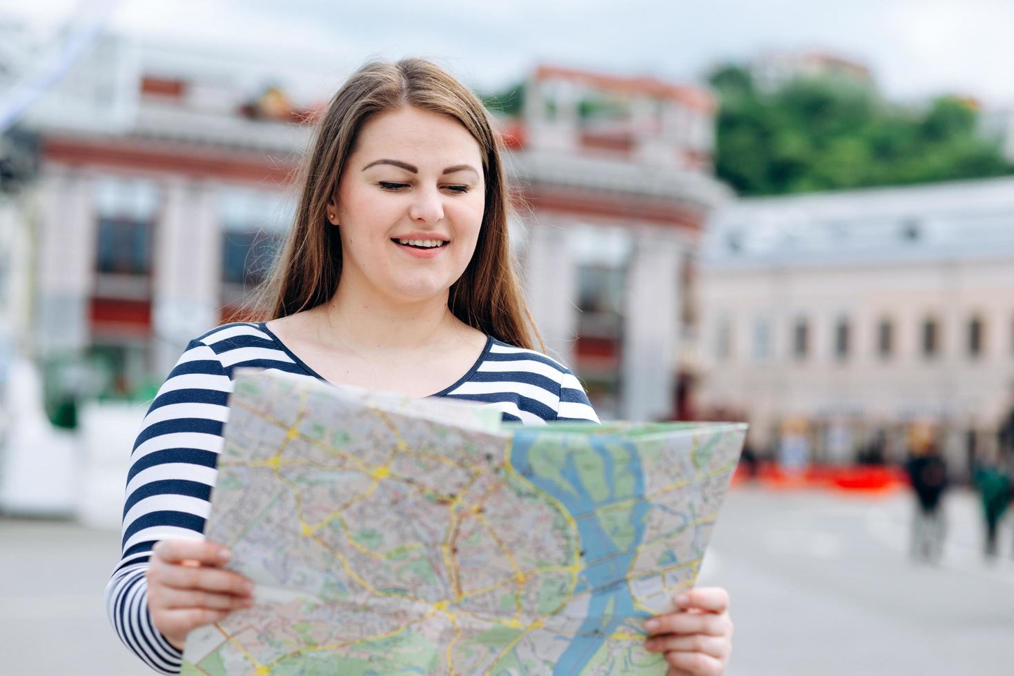 schöne Touristin mit einer Karte in der Hand mitten auf der Straße im Freien foto