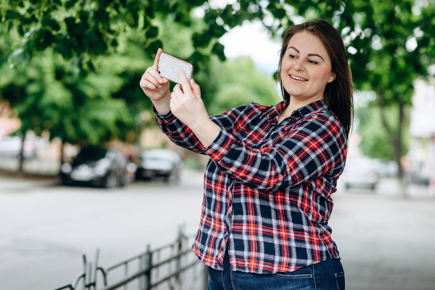 glückliche junge Frau auf Stadthintergrund, die selfie durch Kamera macht. foto