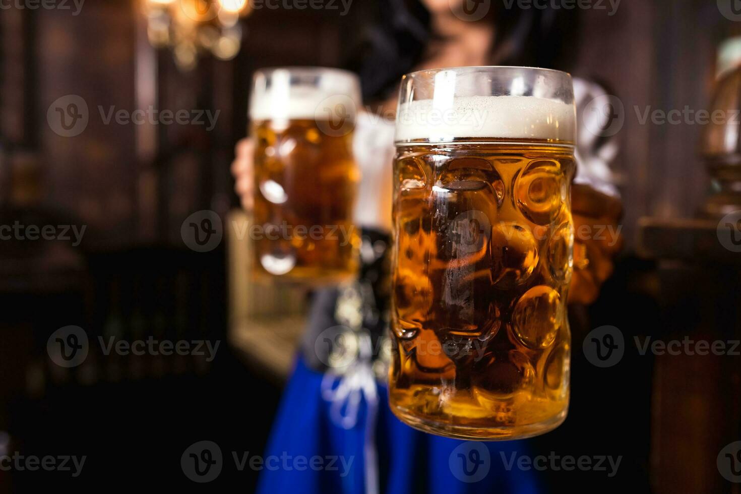 jung sexy Oktoberfest Kellnerin, tragen ein traditionell bayerisch Kleid, Portion groß Bier Tassen beim Bar. foto