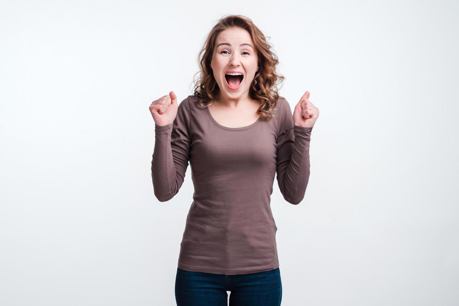 Emotion von Freude, Glück, Mädchen auf weißem Hintergrund in Jeans und T-Shirt. foto