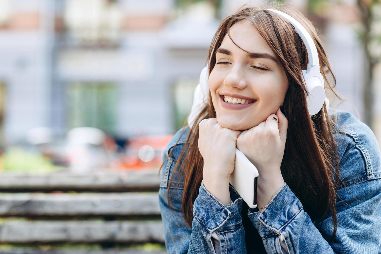 junge, lächelnde Frau, die Musik mit Kopfhörern hört. Mädchen hören Lieder über drahtlose Kopfhörer. Nahaufnahme Gesicht des Teenagers. foto