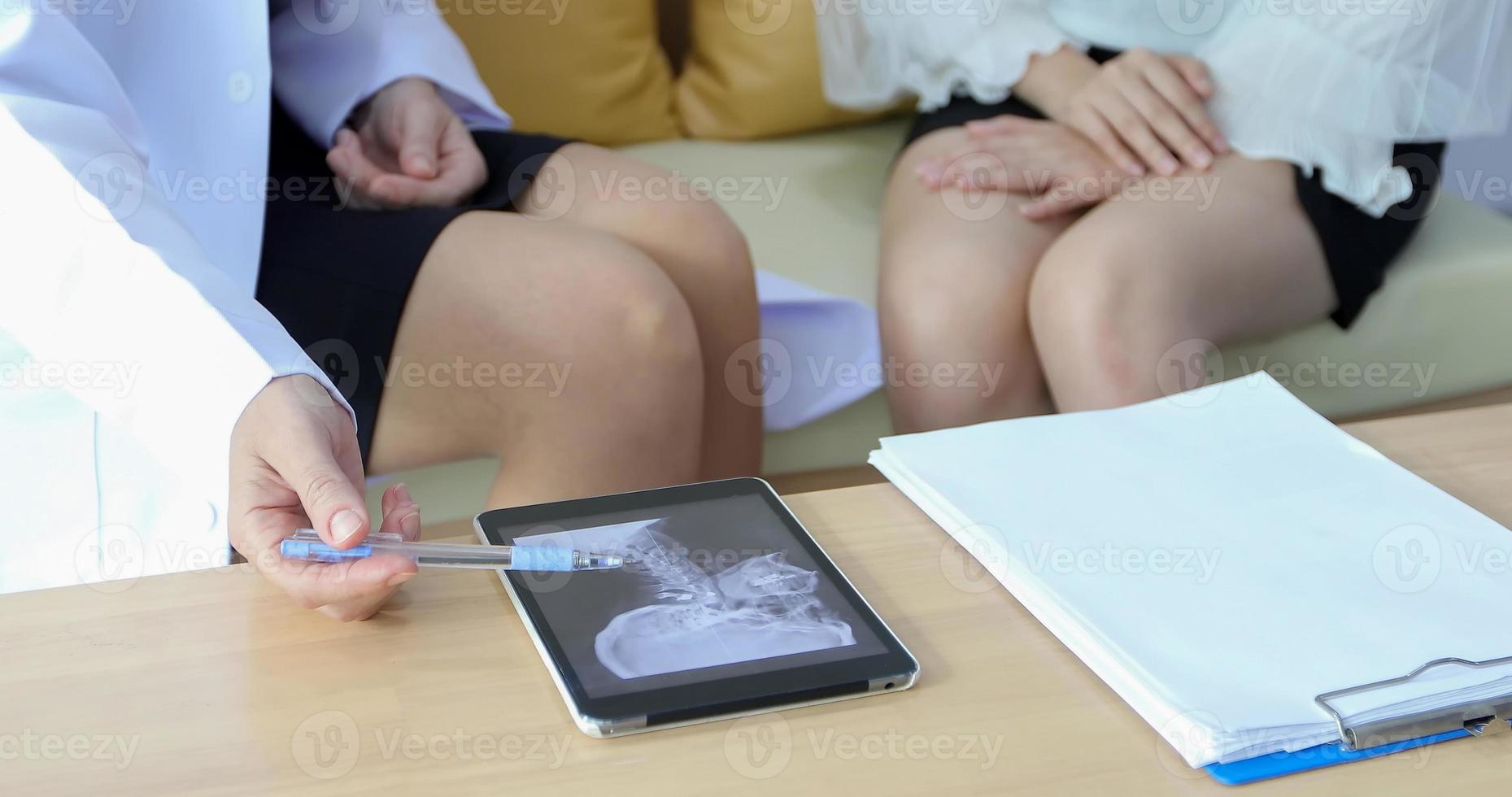 Der Arzt erklärt einer Patientin in seinem Büro in Krankenhäusern die Ergebnisse der Röntgenuntersuchung des Gehirns foto