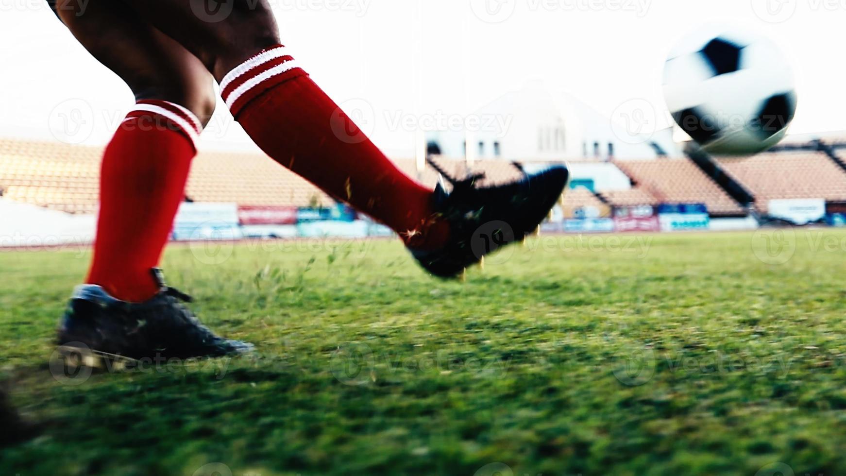 Fußball- oder Fußballspieler, der mit Ball auf dem Feld steht, um den Fußball im Fußballstadion zu treten foto