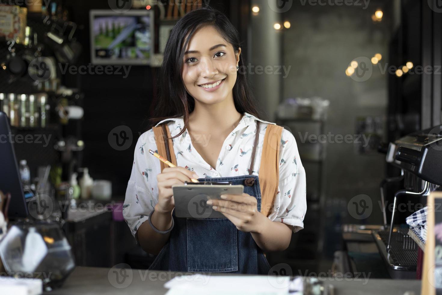 Asiatische Frauen Barista lächelnd und mit Kaffeemaschine in der Cafétheke - berufstätige Frau Kleinunternehmerin Essen und Trinken Café-Konzept foto