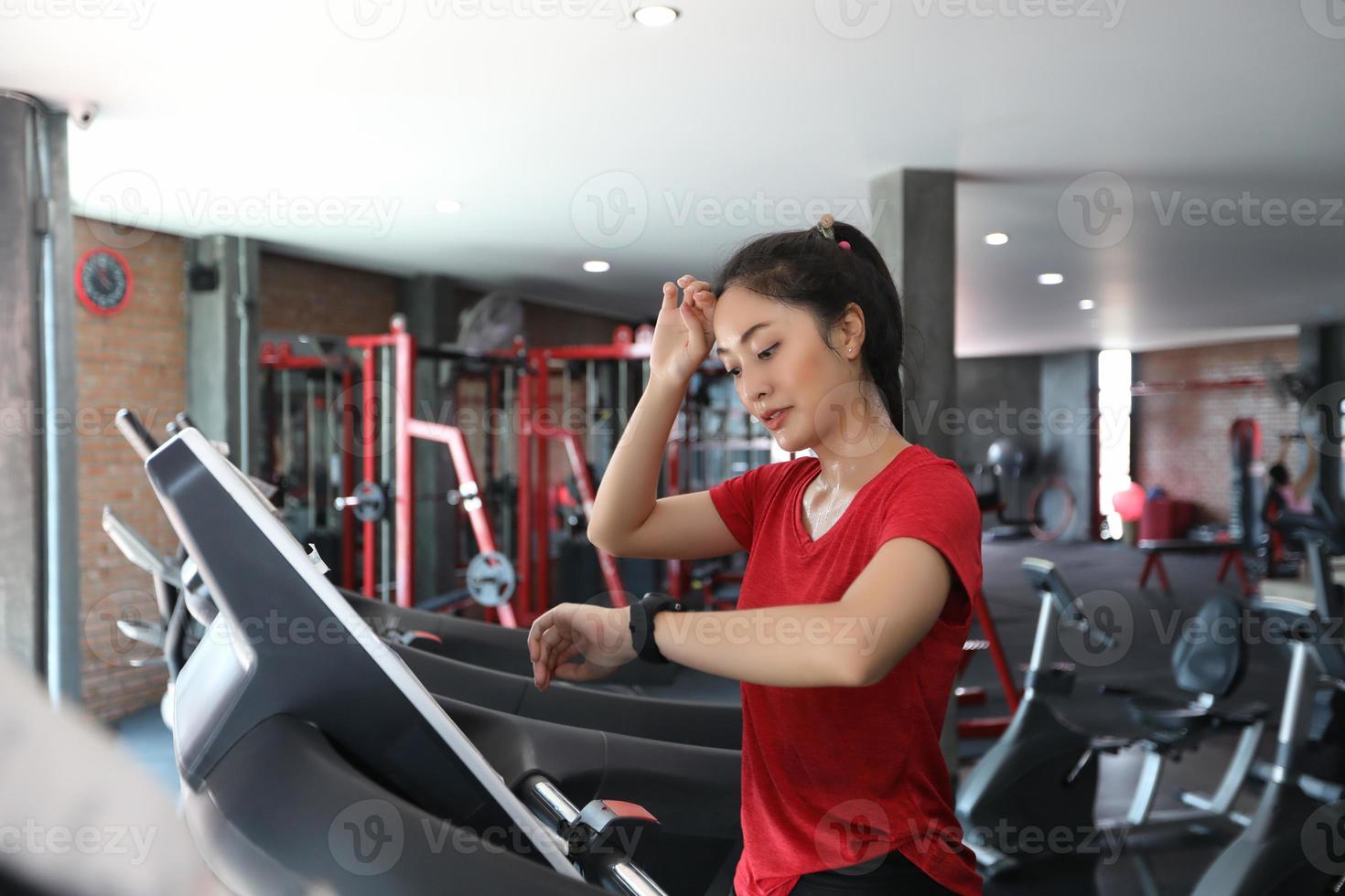 Asiatische Frauen, die Sportschuhe im Fitnessstudio laufen lassen, während eine junge Kaukasierin auf dem Laufband joggt foto