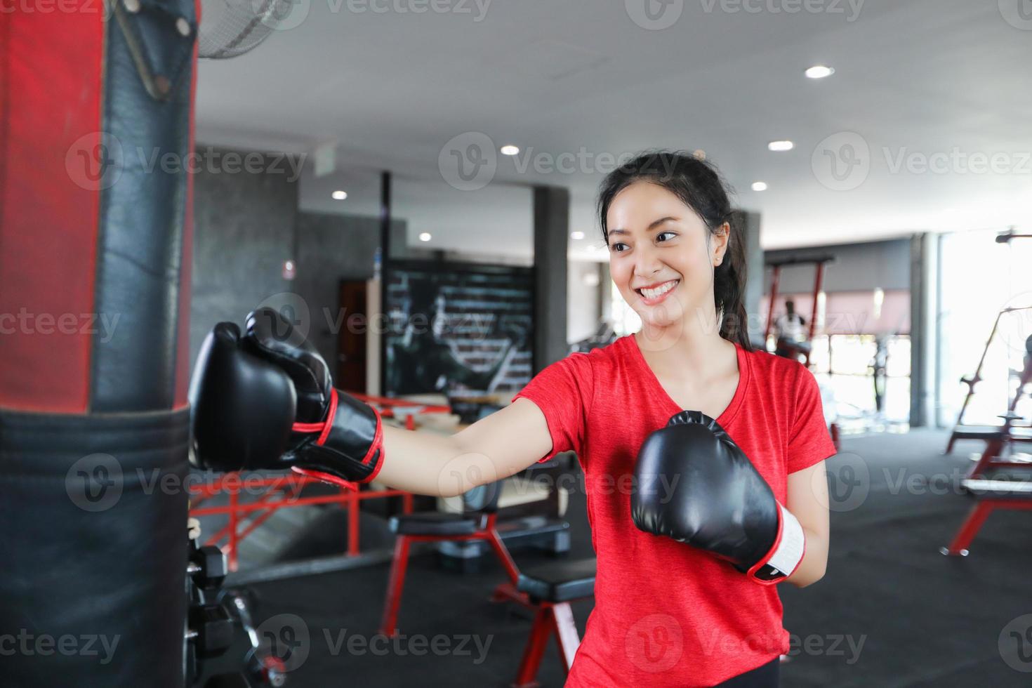 Schöne Frauen asiatischer Boxer glücklich und Spaß beim Fitnessboxen und Stanzen einer Tasche mit Boxhandschuhen. foto