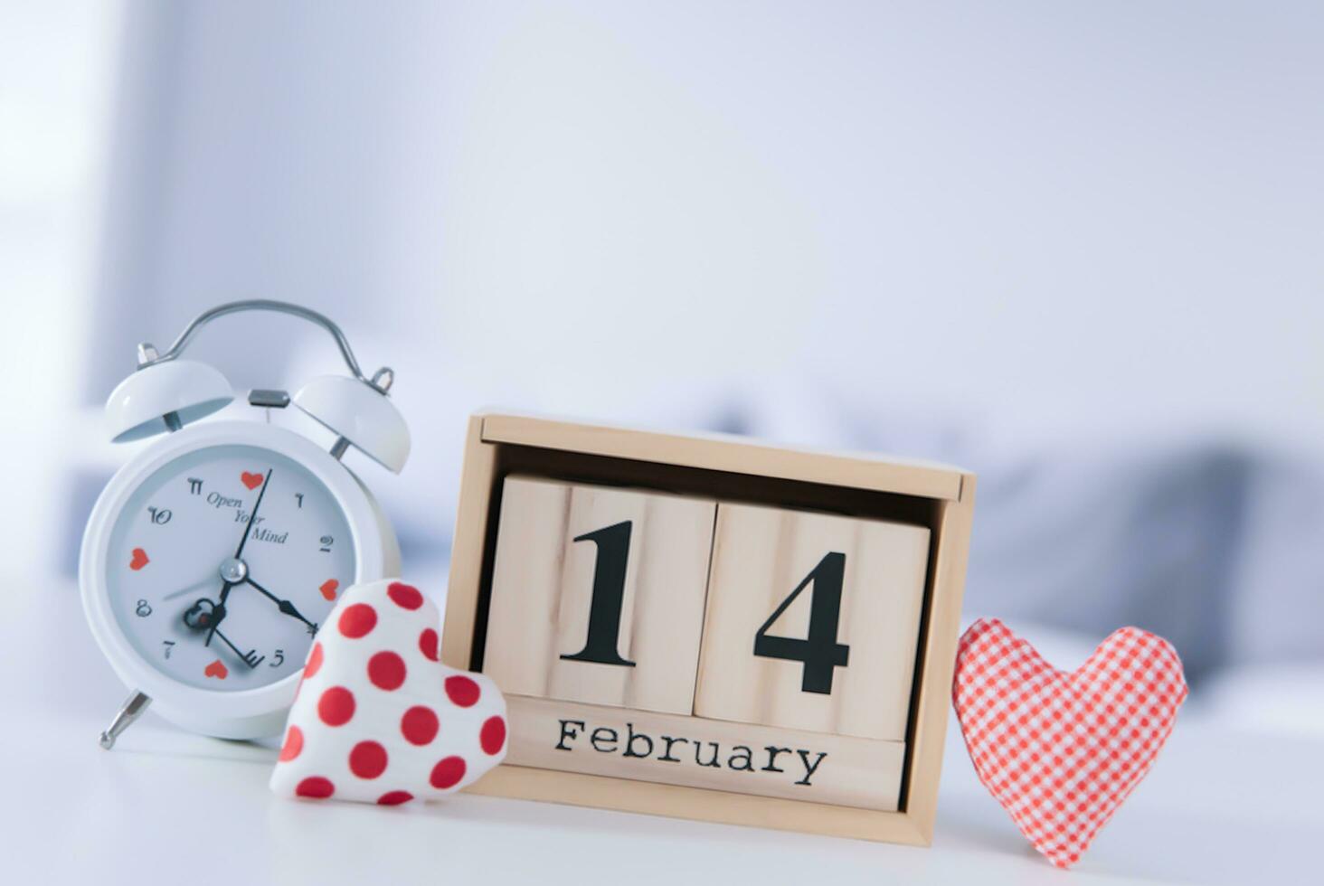 Valentinsgrüße Tag Konzept. Hand machen Garn rot Herz neben hölzern Block Kalender einstellen auf Valentinsgrüße Datum 14 Februar auf Tabelle und hell Zimmer Hintergrund. glücklich Valentinstag Tag. foto