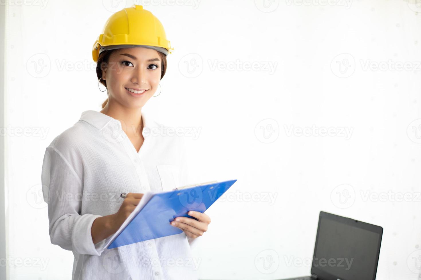 Asiatische Frauen, die Ingenieurinspektion und -Arbeiten und Blaupausen im Büro halten foto