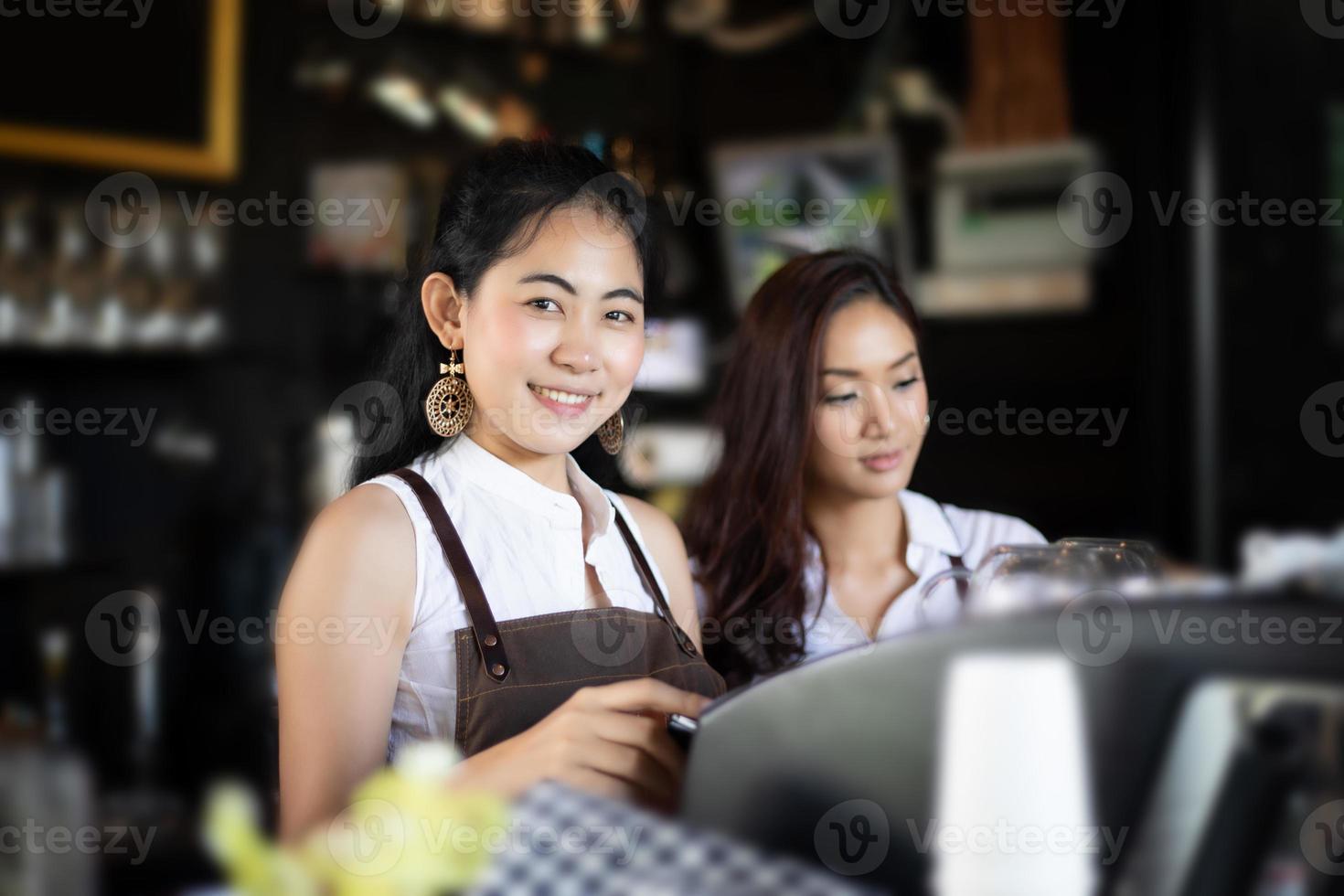 Asiatische Frauen Barista lächelnd und mit Kaffeemaschine in der Cafétheke - berufstätige Frau Kleinunternehmerin Essen und Trinken Café-Konzept foto