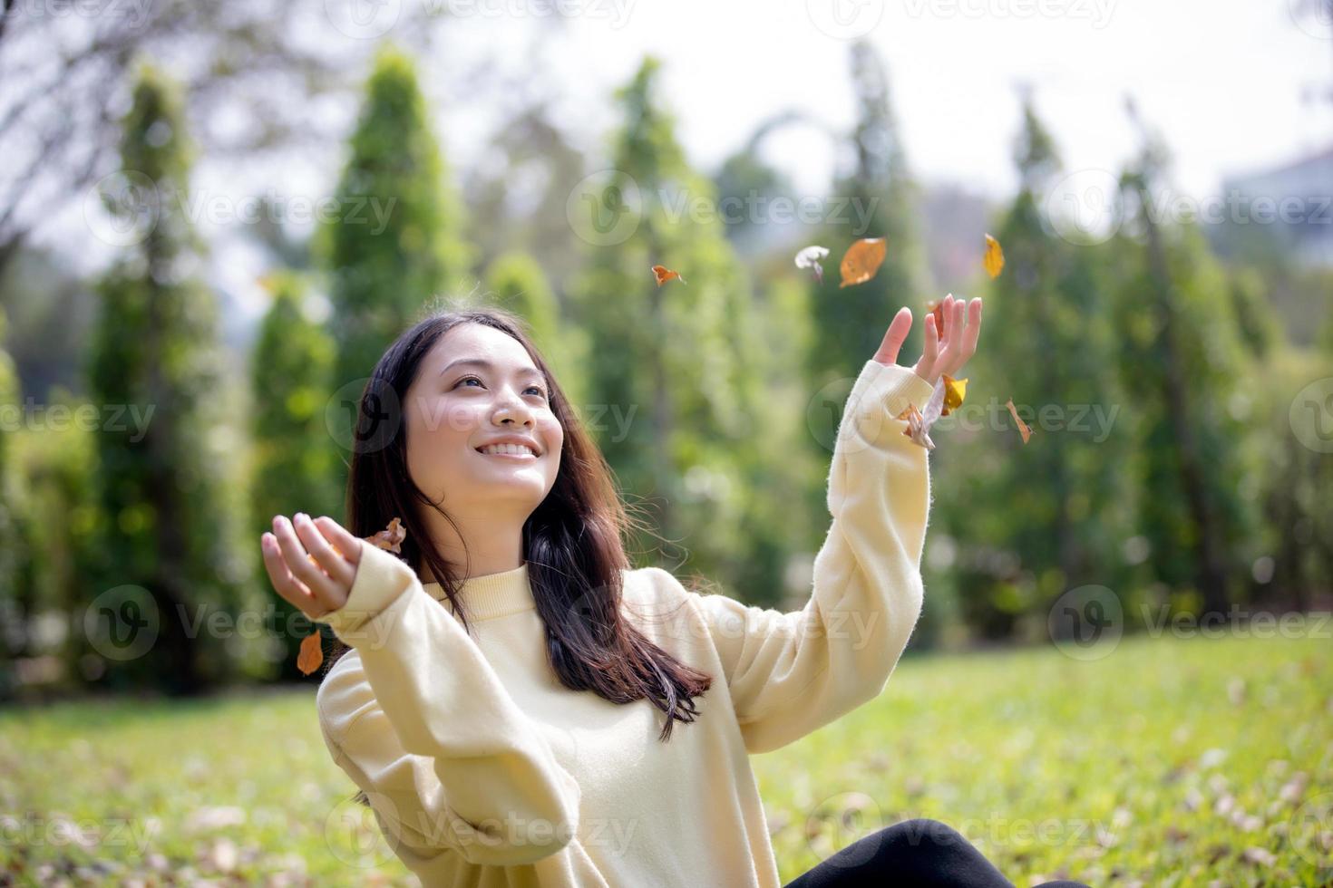 schöne asiatische Frau, die glückliches Mädchen lächelt und warme Kleidung trägt Winter- und Herbstporträt im Freien im Park foto