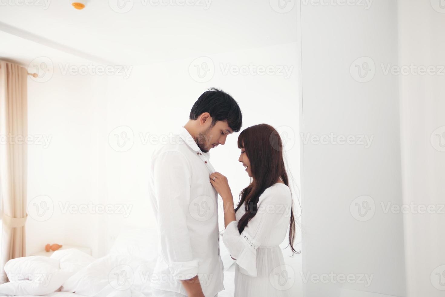 Paarliebhaber, der auf dem Bett Glückslebensstil legt und lächelndes Mädchen im weißen Bett entspannt foto