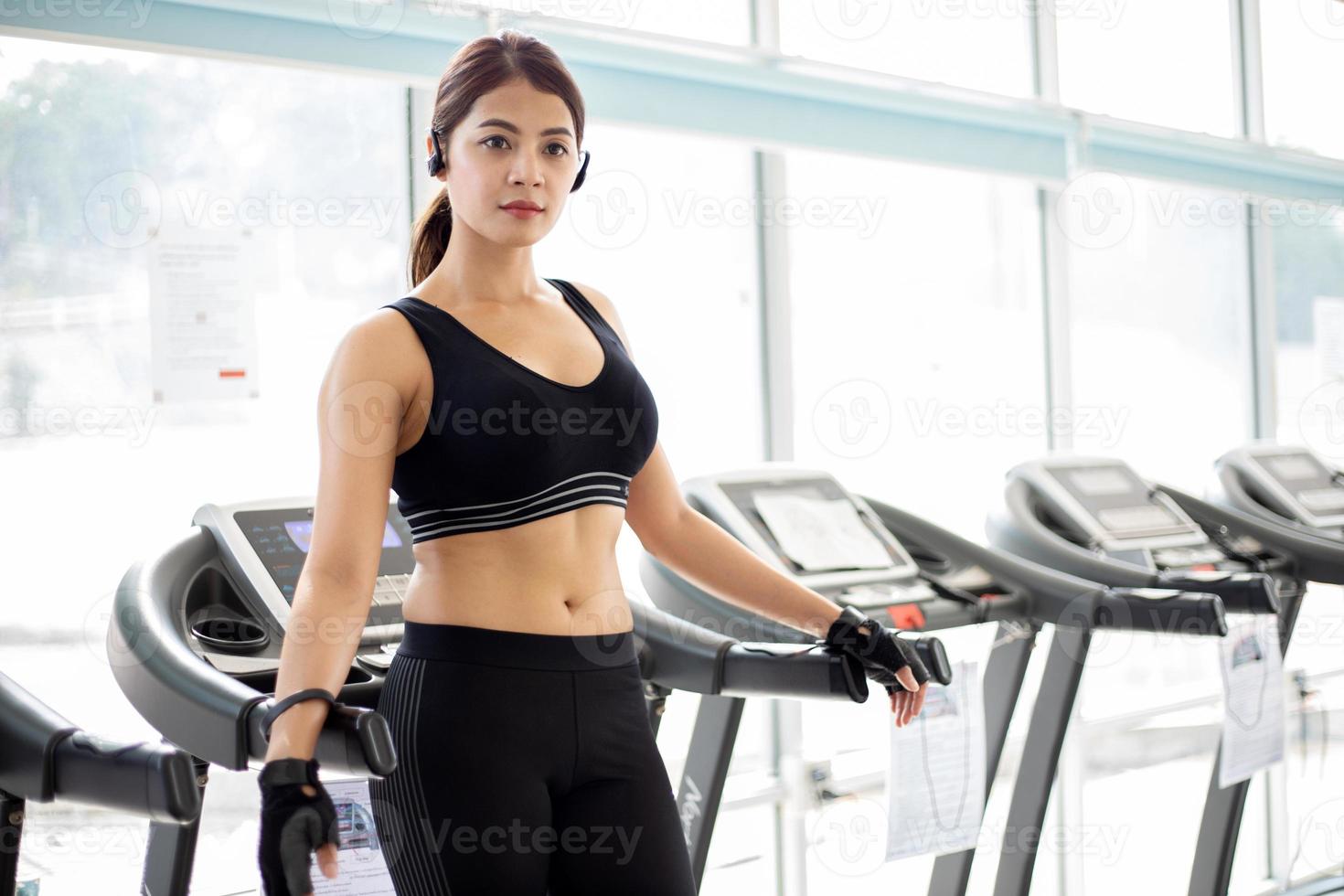 Asiatische Frauen, die Sportschuhe im Fitnessstudio laufen lassen, während eine junge Kaukasierin auf dem Laufband joggt foto