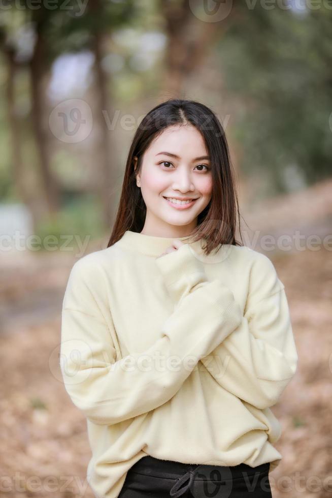 schöne asiatische Frau, die glückliches Mädchen lächelt und warme Kleidung trägt Winter- und Herbstporträt im Freien im Park foto