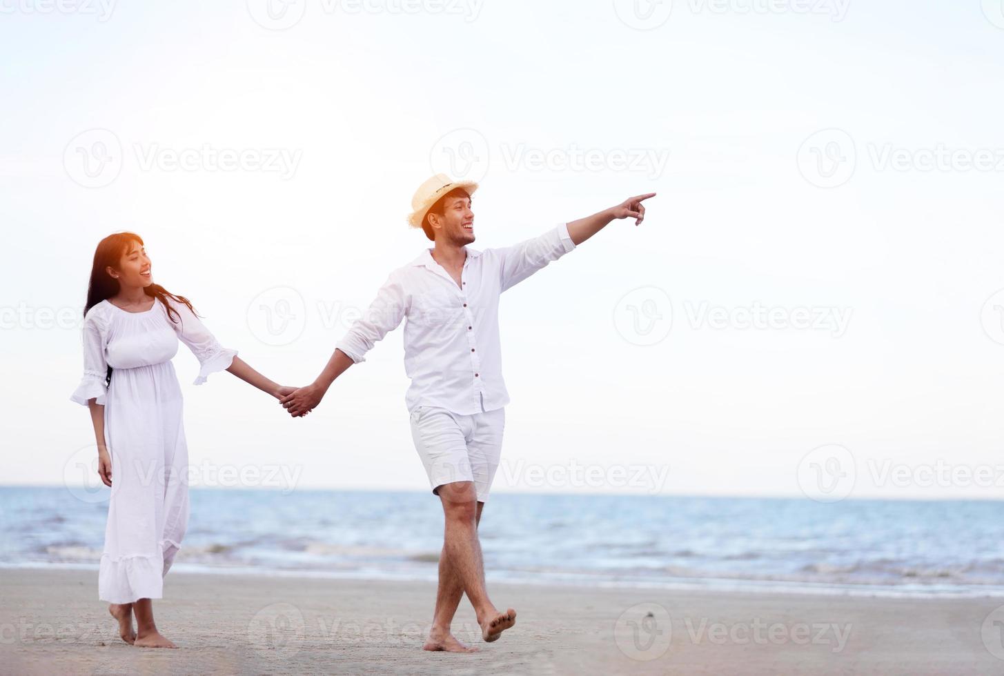 glückliche romantische Paare, die Händchen halten, wenn sie am Strand spazieren gehen? foto