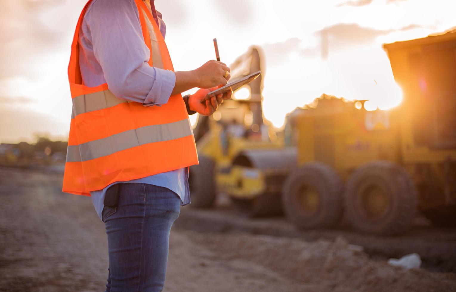 Asiatischer Ingenieur mit Bauarbeiterhelm mit Tablet-PC-Computer, der auf der Baustelle inspiziert und arbeitet foto