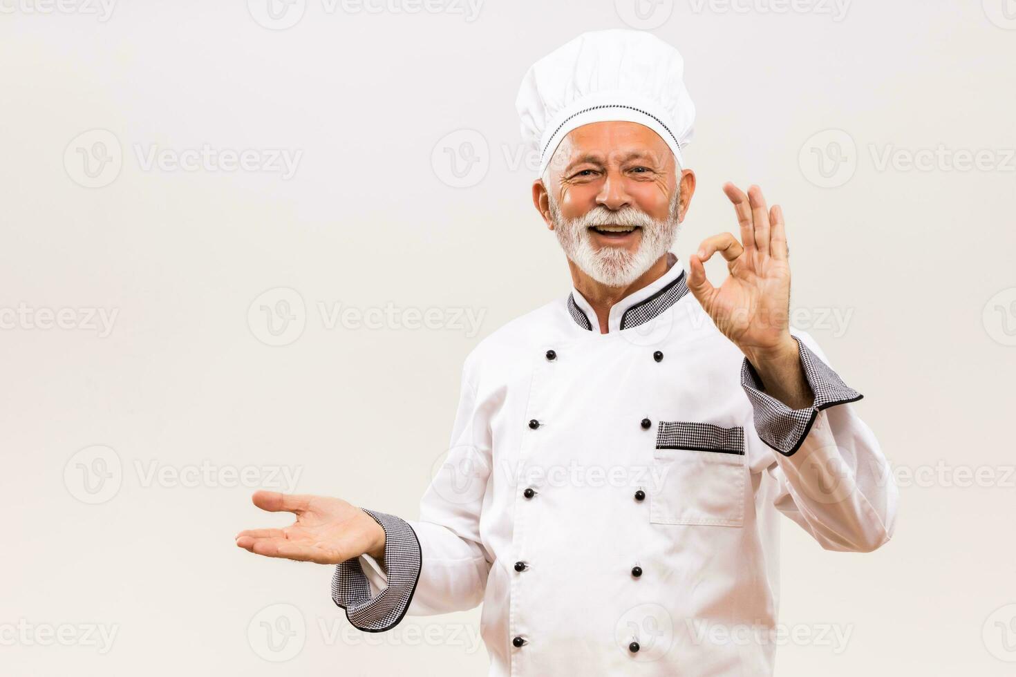 Porträt von Senior Koch zeigen Palme von Hand und in Ordnung Zeichen auf grau Hintergrund. foto