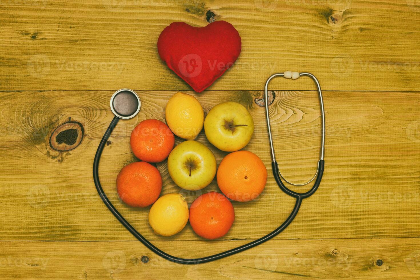 Bild von Obst, Stethoskop und Herz gestalten auf hölzern Tisch.getönt Foto. foto