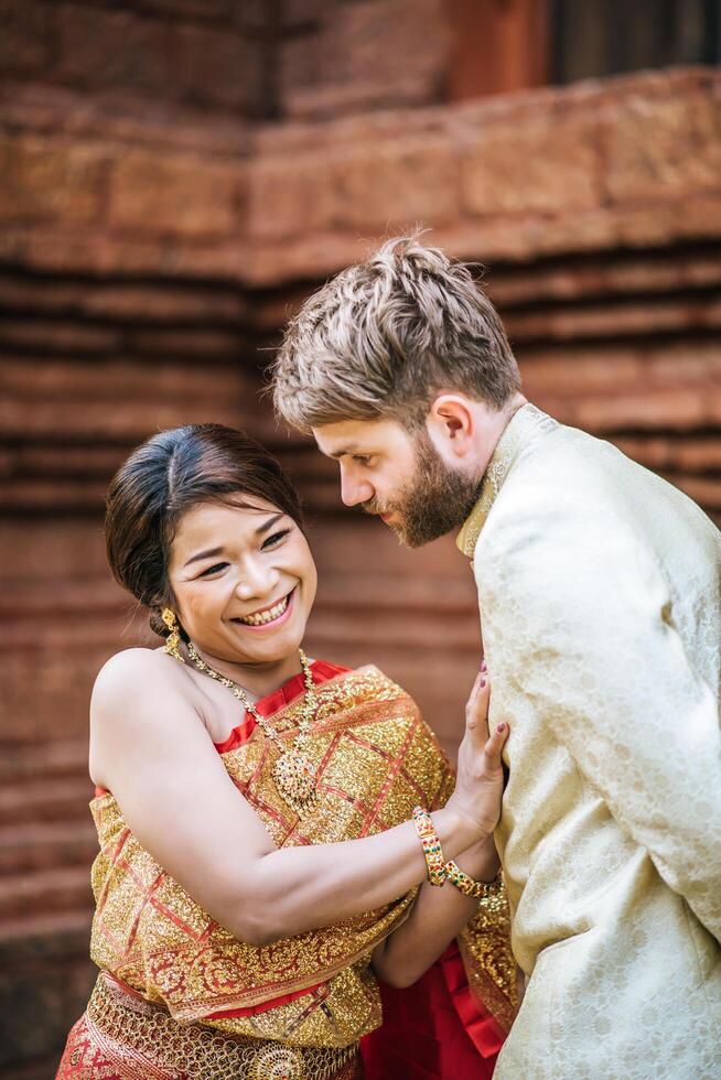 asiatische braut und kaukasischer bräutigam haben romantische zeit mit thailandkleid foto