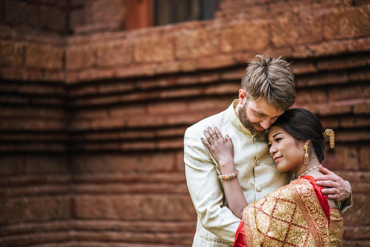 asiatische braut und kaukasischer bräutigam haben romantische zeit mit thailandkleid foto